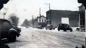 Downtown Kingsley in the 1930s. The building furthest away, north of M113, was Hooper's tavern, where Katy's folks first lived when they moved to Kingsley. The Cleland Tavern, where movies were shown on the painted screen on the building's side, is now where the auto supply store sits. Image courtesy of the Floyd Webster Historical Photograph Collection, http://localhistory.tadl.org/items/show/605
