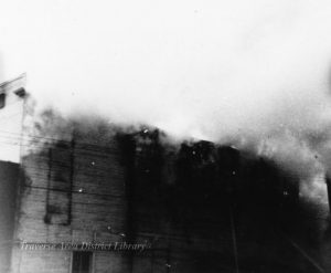 Image of the 1896 fire, actively burning frame buildings on the north side of Front Street. From the Local History Collection, Traverse Area District Library.